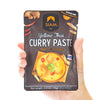 Hand holding a package of Siam Yellow Thai Curry Paste on a white background